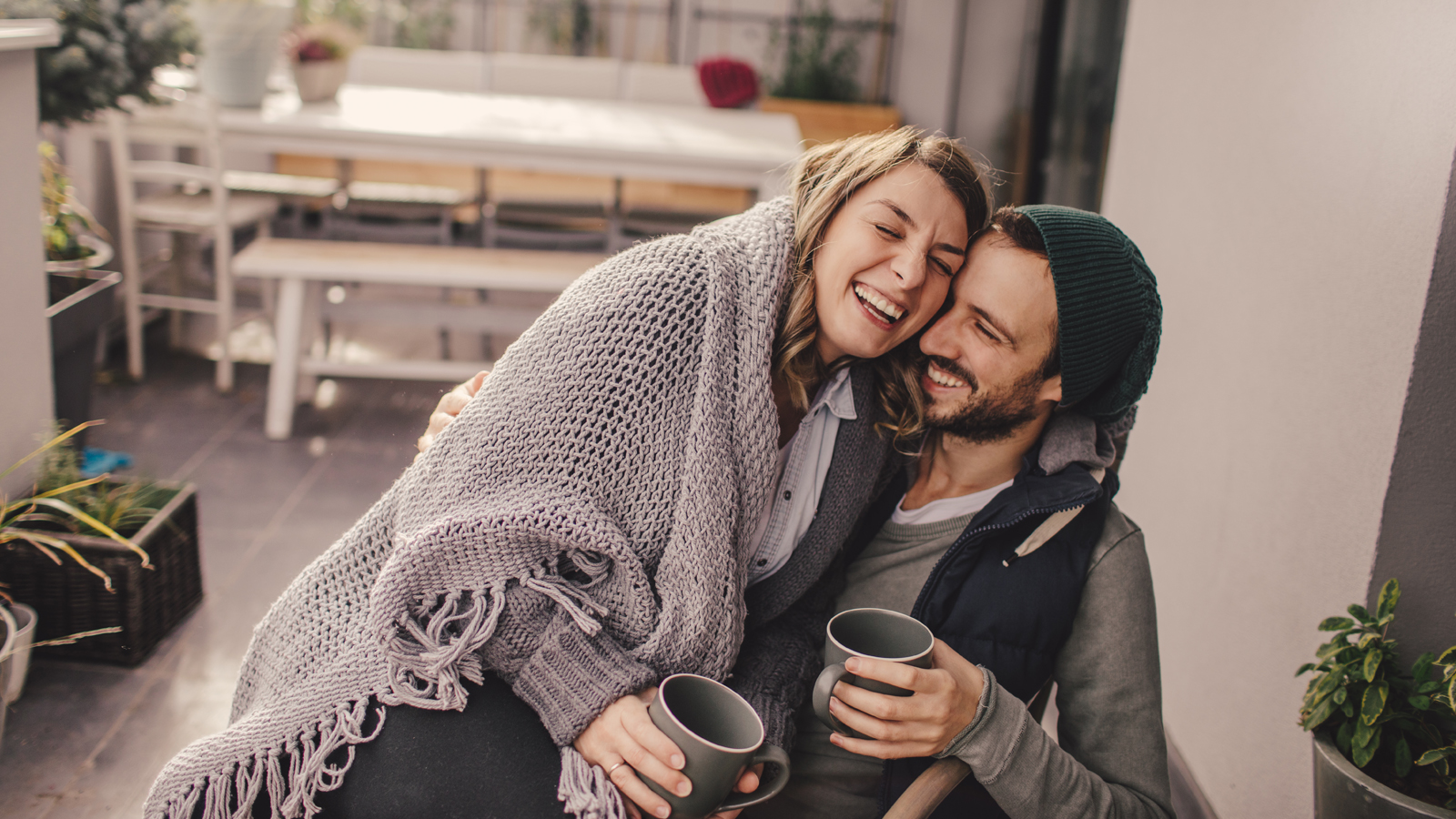 Un jeune couple est assis ensemble, se serre dans les bras, boit une tasse de thé et sourit, heureux d’avoir réussi à arrêter de fumer.